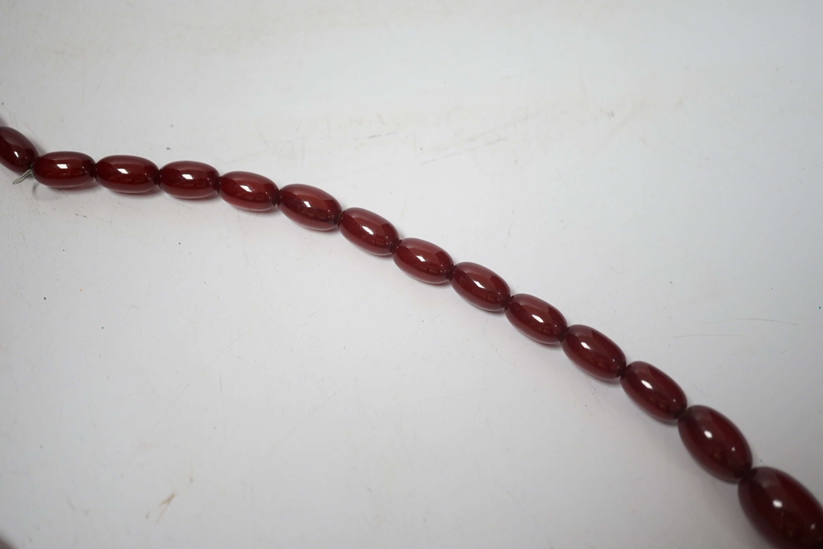 A single strand graduated oval simulated cherry amber bead necklace, 70cm, gross weight 63 grams.